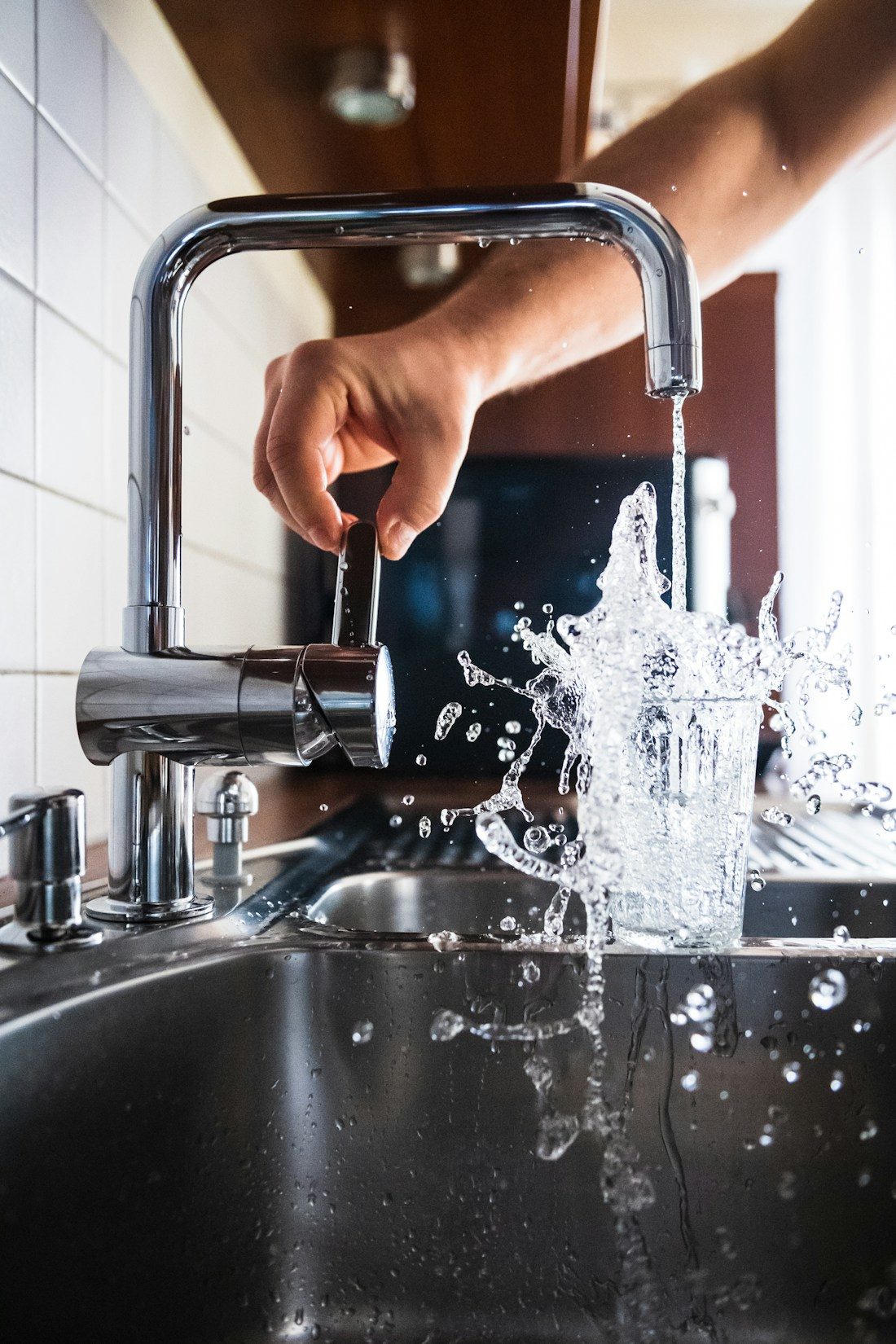 Water running from a chrome kitchen tap into a sink